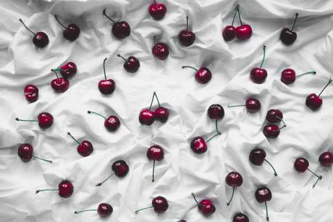 Top view of a cherry on a crumpled white background of bed linen. Stock Photos