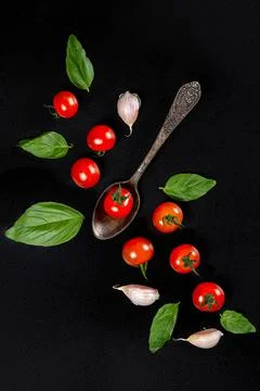 Top view, cherry tomatoes, garlic and basil leaves on a black background Stock Photos