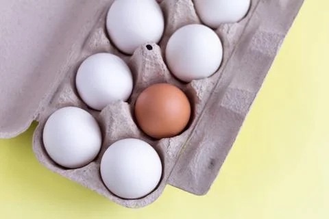 Top view of chicken eggs in an egg box on yellow. Fresh chicken eggs with cop Stock-Fotos