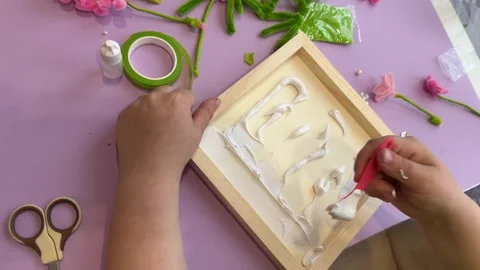 Top view of a child hand using a red spatula to spread white glue Stock-Footage 342347720