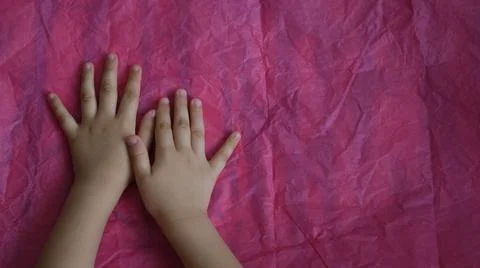 Top view of child hands touch pink crumpled paper on table with copy space Stock Photos