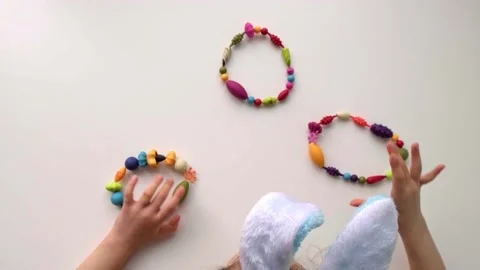 Top view of children hands is playing with color wreaths and eggs from the beads Video stock 171228388
