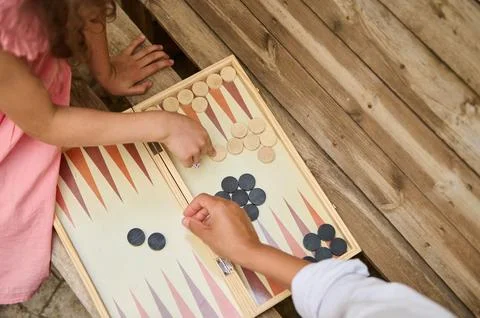 Top view of children playing backgammon on a wooden table outdoors Stock Photos