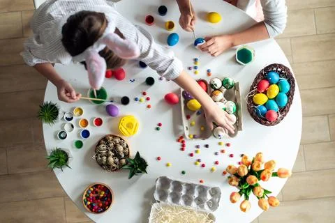 Top view, children at the table paint Easter eggs, paints, work atmosphere. Stock Photos