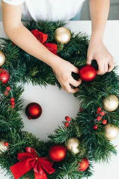 Top view of children's hands decorating Christmas wreath with red Christmas toys Stock Photos