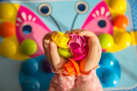 Top view of a child's hand playing with a colorful board game. Child assembli 库存照片