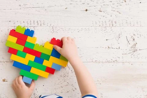 Top  view  on child's hands playing with bright heart made of  colorful plast Stock Photos