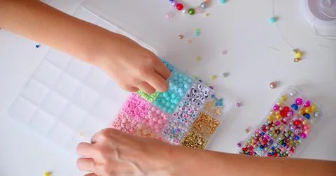 Top View of Childs Hands Stringing Beads for Craft Project 库存照片