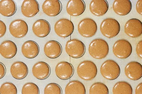 Top View of Chocolate Macaron Shells Piped on Silicone Baking Mat Ready for Baki Stock Photos