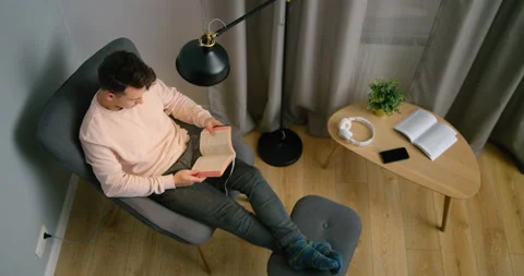 Top View of Christian Man Reading Holy Bible in Armchair at Home at Night Stock Footage 143734143