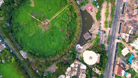 Top view of a city landscape featuring a circular area with green grass and tree Stock Footage 287776549