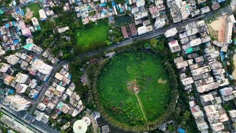 Top view of a city landscape featuring a circular area with green grass and tree Stock Footage 287777605