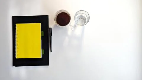 Top view of a clean white desk with a yellow spiral notebook on a black folde Foto stock