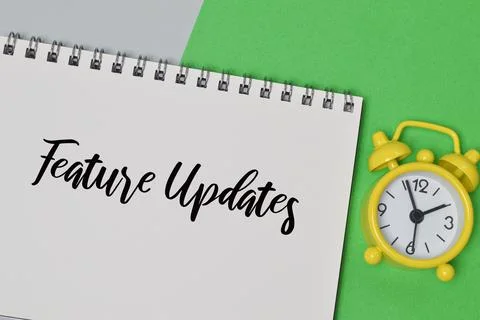 Top view of clock and notebook written with FEATURE UPDATES. Foto stock