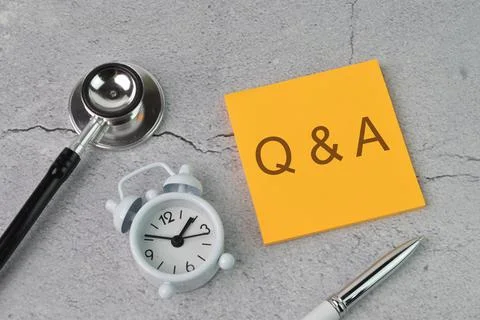 Top view of clock, stethoscope and memo note written with Q&amp;A Stock-Fotos