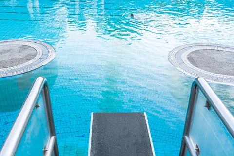 Top view close-up on a diving board against the background of a pool with blu Stock Photos