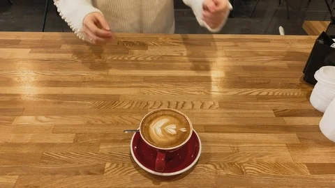 Top view. Close up of hand taking coffee of red cup on wood table. Coffee art Video stock 123553255
