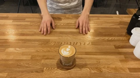 Top view. Close up of hand taking coffee of  cup on wood table. Coffee art latte Video stock 123553272