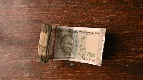 Top View Close-Up of a Man Placing 500/- Currency Note Bundles on Wooden Table Stock-Footage 329343944