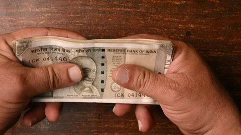 Top View Close-Up of a Man Placing 500/- Currency Note Bundles on Wooden Table Stock Footage 329346969