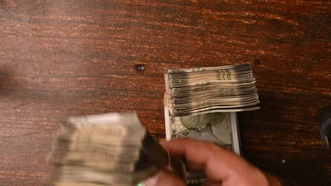 Top View Close-Up of a Man Placing 500/- Currency Note Bundles on Wooden Table Stock Footage 329353849
