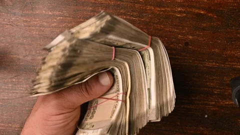 Top View Close-Up of a Man Placing 500/- Currency Note Bundles on Wooden Table Stock Footage 329357860