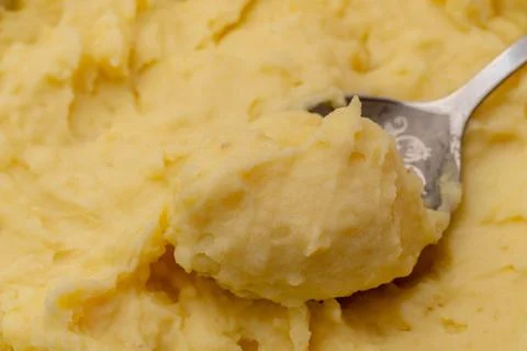 A top view close up of mashed yellow potatoes texture with spoon in it Stock Photos