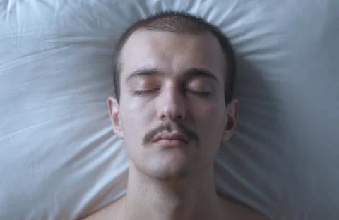 Top View Close-Up Portrait of Young Man Sleeping Peacefully in Bed 스톡 사진