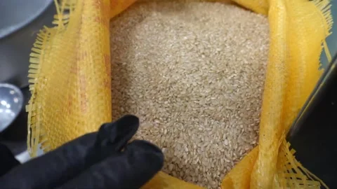 Top view close up of raw brown rice grains inside a large open yellow burlap sac Video stock 343028588
