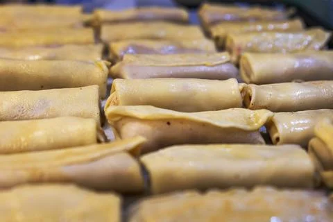 A top-view close-up of several rows of neatly rolled crepes filled with meat, Stock Photos