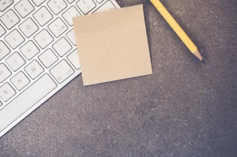 A top view closeup of a computer keyboard with sticky notes and a pencil on a Foto stock