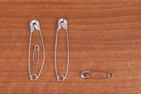 Top view closeup of different size pins on a wooden surface Foto stock