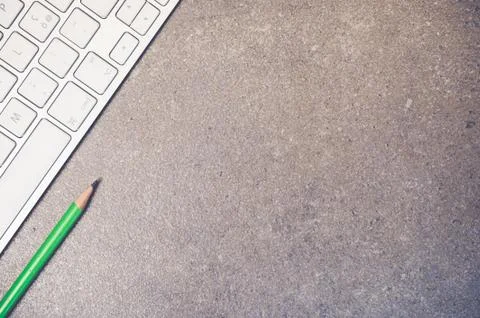 A top view closeup of the keyboard of a computer and a green pencil on a ston Stock Photos