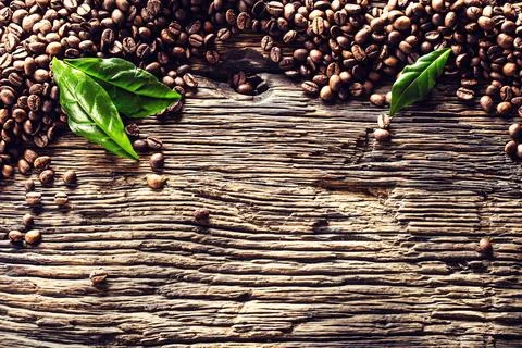 Top of view coffee beans and green leaves on rustic oak table Stock Photos