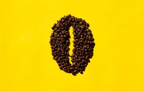 Top view of coffee beans in bean shape with yellow background. Stock Photos