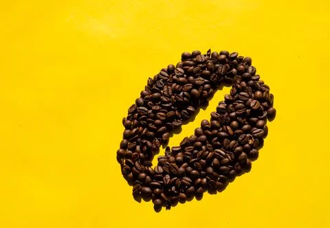 Top view of coffee beans in bean shape with yellow background. Stock Photos