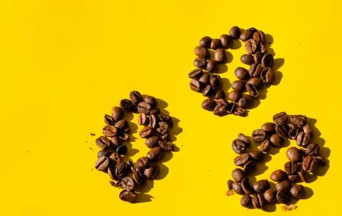 Top view of coffee beans in the form of beans on yellow background. Stock Photos