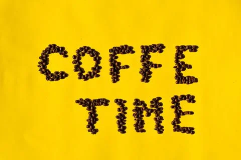 Top view of coffee beans in the shape of letters reading "coffee time" on yel Stock Photos