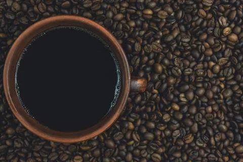 Top view of coffee cup surrounded by roasted coffee beans Stock Photos