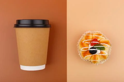 Top view of coffee or tea in brown cardboard cup with pastry against brown and Stock Photos