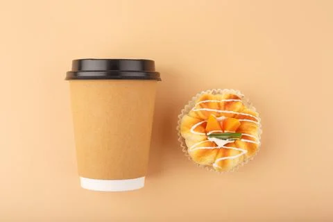Top view of coffee or tea in brown cardboard cup with pastry against beige Stock Photos