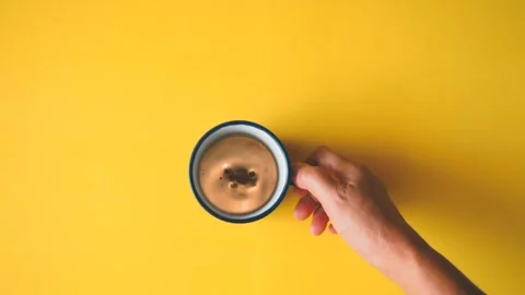 Top view coffee splash in coffee cup over yellow background. Видео 106617859