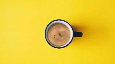 Top view coffee splash in the cup over yellow background. Stock Footage