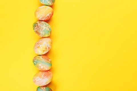 Top view of color easter eggs differen patterns. Line of eggs on yellow Stockfoto's