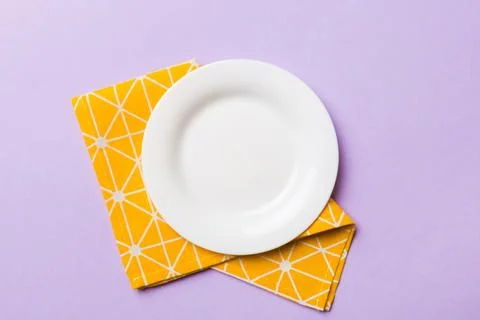 Top view on colored background empty round white plate on tablecloth for food Stock Photos