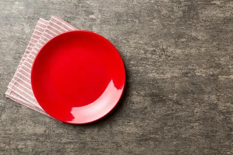 Top view on colored background empty round red plate on tablecloth for food.  Stock Photos