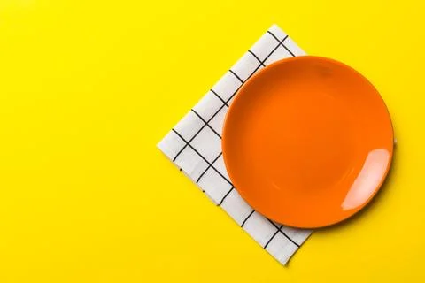 Top view on colored background empty round red plate on tablecloth for food.. Stock Photos