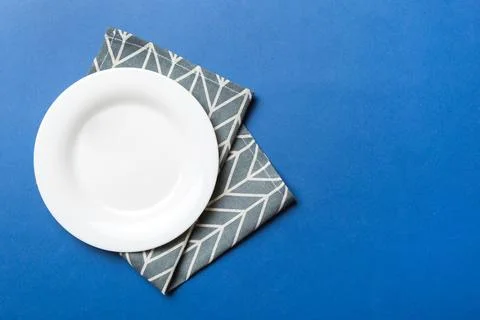 Top view on colored background empty round white plate on tablecloth for food Stock Photos