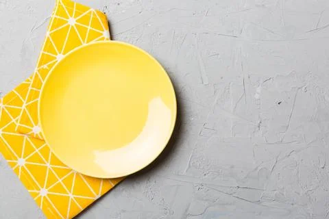 Top view on colored background empty round yellow plate on tablecloth for f.. Stock Photos