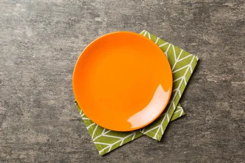 Top view on colored background empty round red plate on tablecloth for food.  Stock Photos